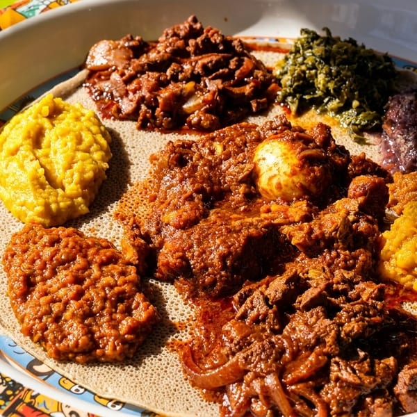 A colorful platter of Ethiopian food, including injera bread, stews, and vegetable dishes.